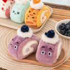 Plush toys resembling cat Swiss rolls with faces on a wooden surface.