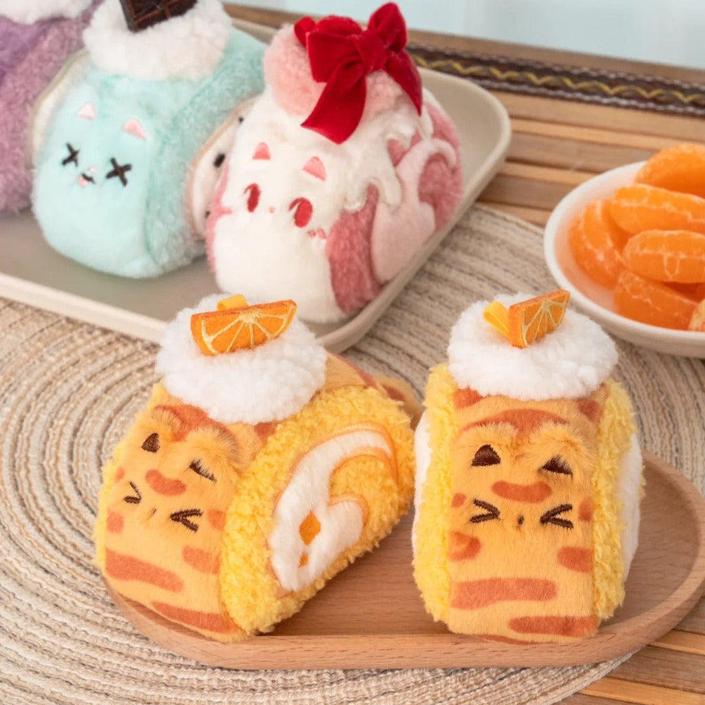 Plush cats shaped like cartoon-style pastries on a wooden surface with a blurred background.