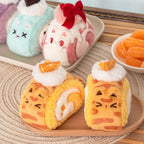 Plush cats shaped like cartoon-style pastries on a wooden surface with a blurred background.