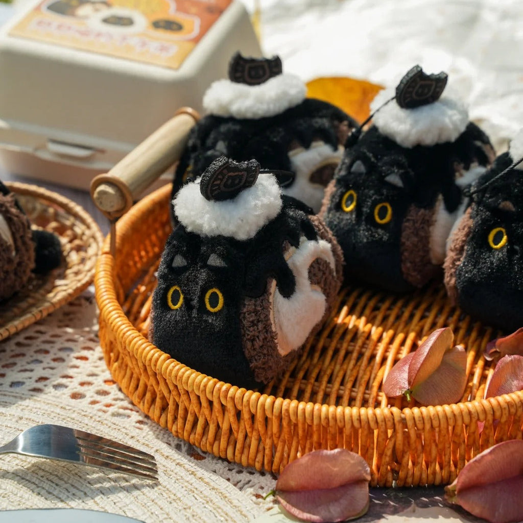 Plush cat toys with black and white fur in a woven basket on a picnic blanket.