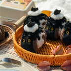 Plush cat toys with black and white fur in a woven basket on a picnic blanket.