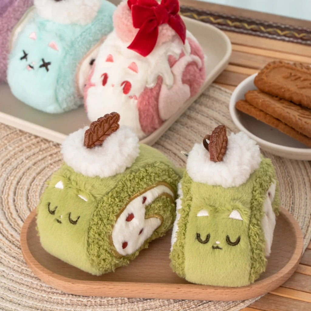 Plush toys resembling cat swiss rolls on a wooden tray with a light background