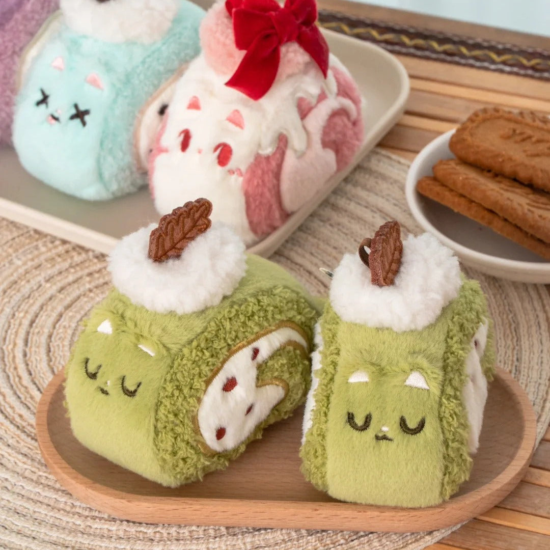Plush toys resembling cat swiss rolls on a wooden tray with a light background