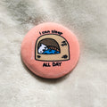 Round pink button badge with a cat illustration and text 'I can sleep all day' on a textured surface.