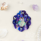 Decorative magnet with a cat and butterfly design on a purple scalloped mica acrylic, surrounded by decorative items.
