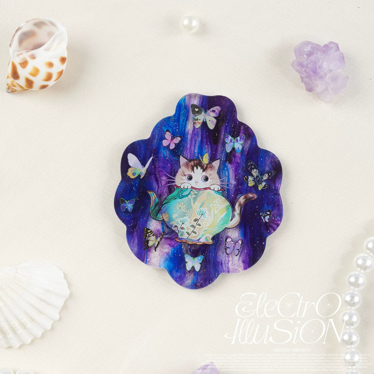 Decorative magnet with a cat and butterfly design on a purple scalloped mica acrylic, surrounded by decorative items.