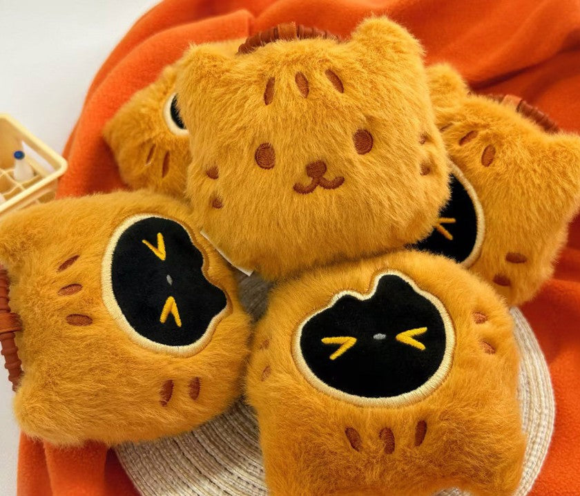 Plush toys resembling cats with black faces on an orange blanket