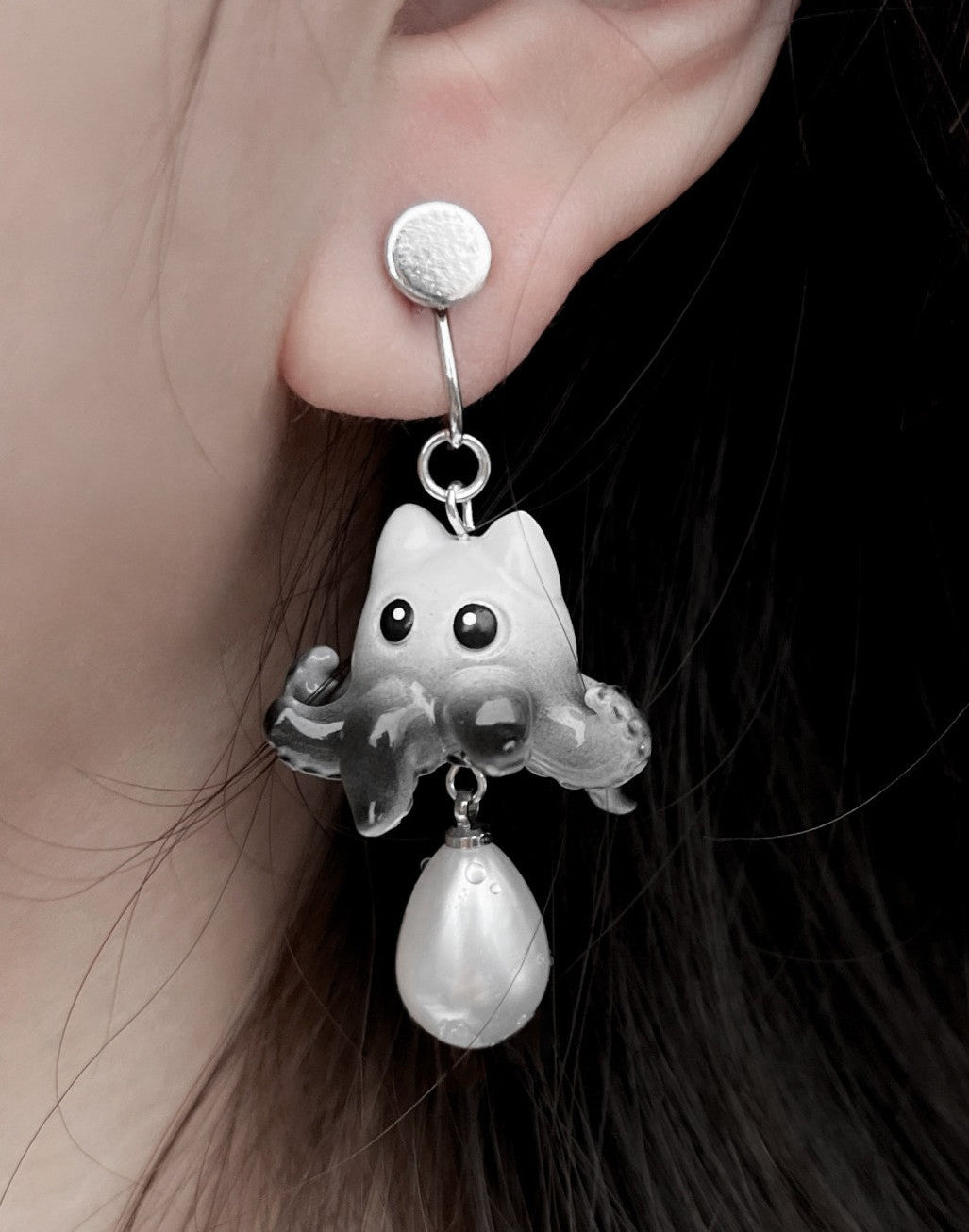 Earring with ghost and pearl design worn by a person