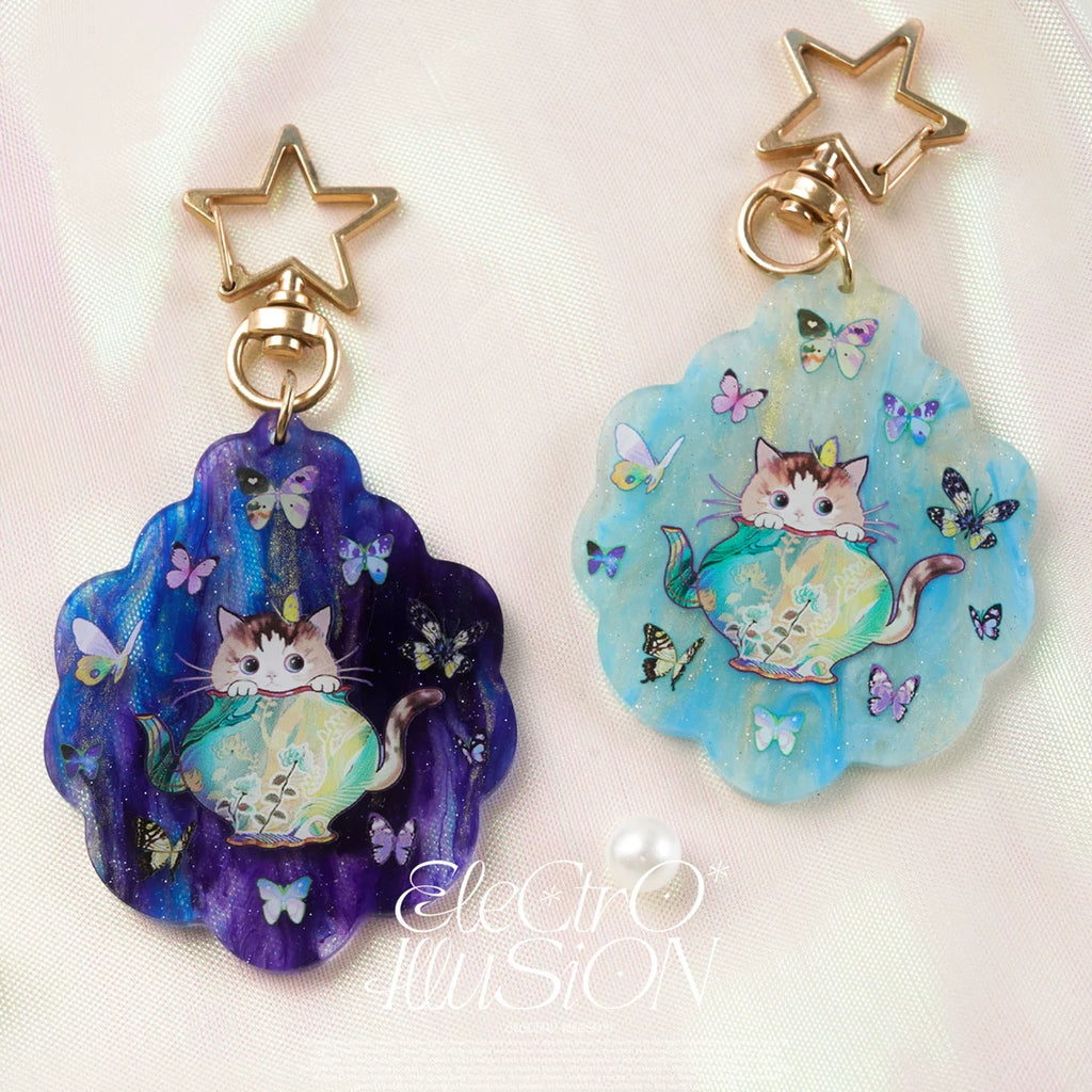 Two colorful cat-themed keychains with star and butterfly designs on a white background.