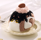 Plush toy resembling a tuxedo cat with an almond on a white plate
