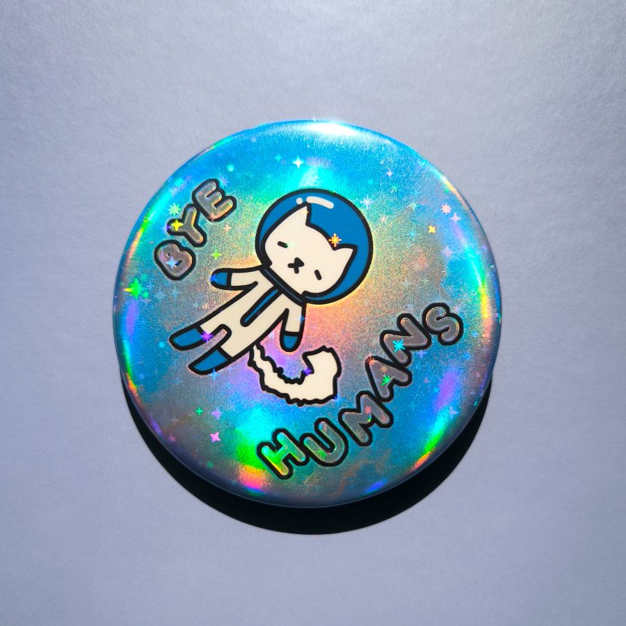 Holographic button with a cat design and text 'BYE HUMANS' on a gray background