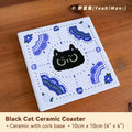 Black cat ceramic coaster with blue patterns on a wooden surface