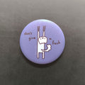 Round purple button pin with a cat character and text 'don't give a fuck' on a dark background