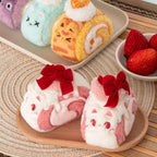 Plush toys resembling dessert rolls with faces on a wooden tray.