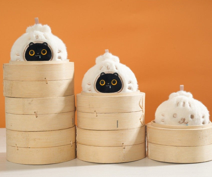 Three cat-shaped steamer buns with bamboo steamers on an orange background