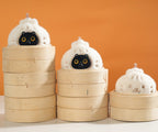 Three cat-shaped steamer buns with bamboo steamers on an orange background