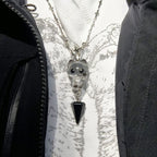 Necklace with a cat-shaped pendant and black triangle on a textured white background